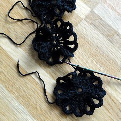 Häkelrock mit Durchblick in schwarzer Farbe, handgefertigt mit filigranen Mustern, auf Holzuntergrund fotografiert, geeignet für Handmade- und Modebegeisterte.
