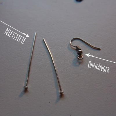 Zwei silberne Ohrhänger und eine Niete, handgefertigte Schmuckstücke, für Ohrschmuck, kreative DIY-Accessoires, Schmuckdesign, handgemacht, modischer Ohrschmuck.