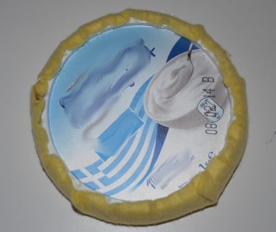 Kunststoffflasche, weißer Hut und blauer Pinsel auf einem runden, gelb ummantelten Gegenstand, geeignet für ein DIY Blumenkostüm.