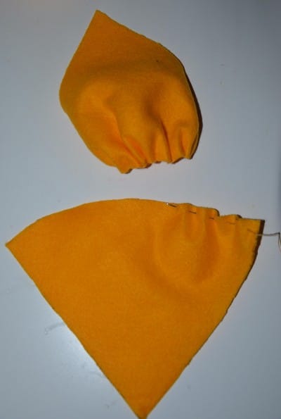 Zwei orange Stoffstücke, die als Blütenblätter für ein DIY Blumenkostüm verwendet werden, mit sichtbaren Nähten und Stoffstruktur.