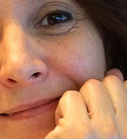 Nahaufnahme eines lachenden Gesichts mit sichtbaren Sommersprossen, freundlicher Ausdruck, handgemachte Kultur, kreative Handarbeit, authentisch und herzlich.