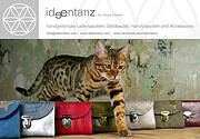 Handgefertigte Ledertaschen in verschiedenen Farben, begleitet von einer Katze, die eine Tasche berührt, auf einem Holztisch, ideal für handgemachte Accessoires.