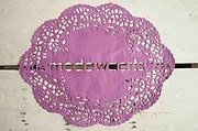Filigrane, handgefertigte Spitze in lila mit dem Schriftzug "modewachs" für kreative Handwerkskunst und Textildesign.