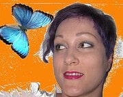 Porträt einer Frau mit kurzen dunklen Haaren und rotem Lippenstift, neben einem blauen Schmetterling auf orangefarbenem Hintergrund, symbolisiert kreative Handarbeit.