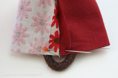 Detailaufnahme eines handgenähten Stoffhuhns mit bunten Stoffmustern, Nadel und Faden, geeignet für Nähanleitungen und DIY-Projekte.