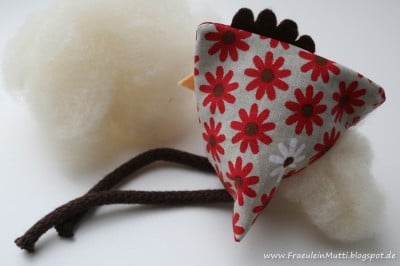 Niedliches Stoff-Küken aus Baumwolle mit rotem Blumenmuster, braunem Schnabel und weißen Wollfüßen, ideal für Handmade-Dekorationen oder als Nähprojekt.