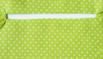 Grüner Stoff mit weißen Punkten, zeigt eine Naht und eine Tasche, passend zum Sew Along Tag 3: Plissee und Innentasche nähen.