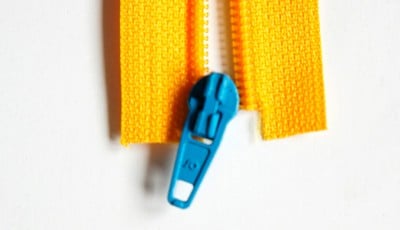 Blauer Reißverschluss zwischen zwei gelben Stoffstreifen, ideal für die Herstellung einer Clutch im Sew Along Tag 4.