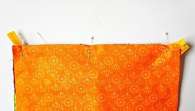 Bunter Stoffzuschnitt mit orangefarbenem Muster für eine selbstgenähte Clutch, vorbereitet für den Sew Along Tag 4 - Clutch zusammenstellen.