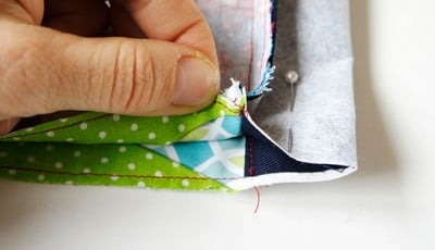 Detailaufnahme beim Zusammenfügen von Stoffstücken für eine Clutch, Nähfaden und Stoffe in verschiedenen Mustern sichtbar, im Rahmen eines Nähprojekts.