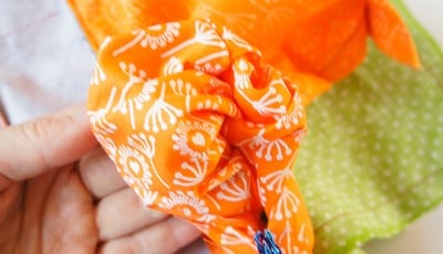Bunte Stoffe für eine selbstgenähte Clutch, die beim Sew Along Tag 4 - Clutch zusammenstellen verwendet wird, mit orange, grün und weißen Mustern.