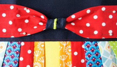 Bunte Stoffe mit verschiedenen Mustern und Farben, inklusive rotem Stoff mit weißen Punkten, für die Herstellung einer Clutch im Sew Along Tag 4.