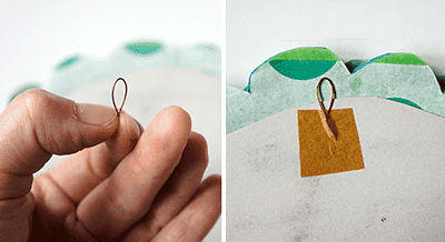 Hand hält eine Schnur mit einer kleinen Schlaufe, daneben fertig zugeschnittene Wabenbälle aus Papier in verschiedenen Farben für DIY Dekorationen.