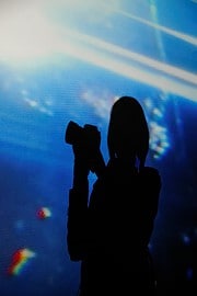 Silhouette einer Person mit Kamera vor einem bunten, abstrakten Hintergrund bei HANDMADE Kultur, kreative Atmosphäre, Kunst, Fotografie, Event, Inspiration.