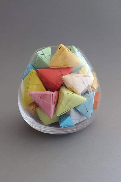 Verschiedene bunte Papier-Glückskekse in einer transparenten Schale, ideal für DIY Glückskekse, Wichteln oder Liebesbotschaften.