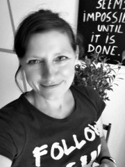 Porträt einer Frau bei HANDMADE Kultur, die kreative Handarbeiten präsentiert, mit inspirierendem Zitat im Hintergrund, Fokus auf handgemachte Kunst und DIY-Projekte.
