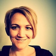 Porträt einer lächelnden Frau mit kurzen, blonden Haaren, die für Handmade Kultur steht, in einem professionellen Umfeld, Fokus auf Kreativität und Handwerkskunst.