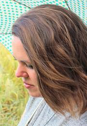 Frau mit braunen, gewellten Haaren, die natürliche Haarpflegeprodukte bei Handmade Kultur verwenden, umweltfreundlich und nachhaltig.