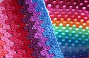 Bunte gehäkelte Decke mit verschiedenen Farben und Mustern, handgefertigt, ideal für gemütliche Heimdekorationen.