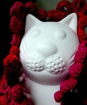 Weiße Keramik-Katzenfigur umgeben von handgestricktem roten und pinken Garn, ideal für handgemachte Dekorationen und kreative Geschenkideen.