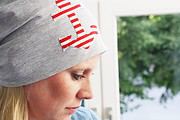Frau trägt handgemachten, gestreiften Stoffhut mit Anker-Design, zeigt kreative Textilkunst, ideal für Handmade- und DIY-Enthusiasten, Fokus auf Handarbeit und Design.