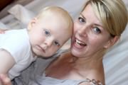 Lächelnde Mutter mit ihrem Kind, beide in entspannter Atmosphäre, zeigt Liebe und Verbundenheit, ideal für Themen wie Familie, Elternschaft und Kinderpflege.
