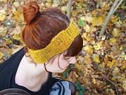 Handgefertigter Wollkopfband in Senfgelb, getragen von einer Frau mit roten Haaren, beim Spaziergang im herbstlichen Laubwald, handgemacht, modisch und warm.