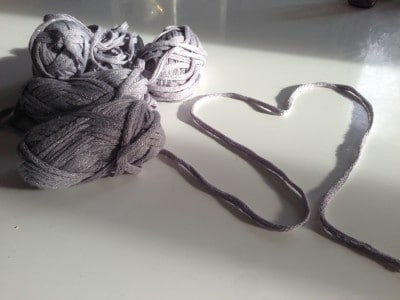 Wolle in Grautönen und ein Herz aus Garn, symbolisch für Handarbeit und Kreativität, passend zum Thema HANDMADE Kultur.