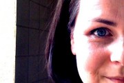 Nahaufnahme eines lachenden Mädchens mit blauen Augen, das handgemachte Kunstwerke präsentiert, symbolisiert kreative Handarbeit und nachhaltiges Design bei HANDMADE Kultur.