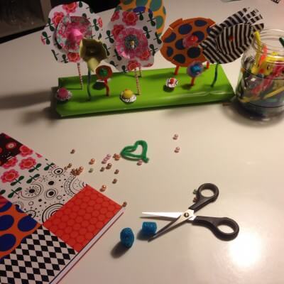 Bunte Papierblumen und Bastelmaterialien für Frühlingsdekoration, inklusive Schere, Perlen und Papiermuster, ideal für kreative DIY-Projekte.
