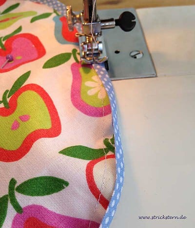 Handgemachtes Baby-Lätzchen mit buntem Apfelmuster, auf einer Nähmaschine genäht, ideal als Last-Minute Babygeschenk.