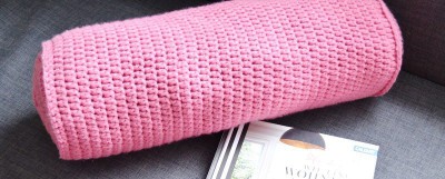Häkelte Nackenrolle in rosa Farbe, handgemacht, ideal für Dekoration und Komfort, passend zum DIY Dekorationsprojekt.