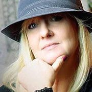 Frau mit Hut, die kreativ und stilvoll handgemachte Kunstwerke präsentiert, ideal für Kunst- und Handwerksliebhaber, die einzigartige, handgefertigte Produkte suchen.