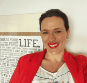 Fröhliche Frau mit dunklen Haaren, rotem Blazer und weißem T-Shirt, die bei Handmade Kultur kreative Handwerkskunst präsentiert.