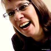 Frau mit Brille lacht herzlich, zeigt Freude und Begeisterung für handgemachte Kunst und kreative Produkte bei HANDMADE Kultur.