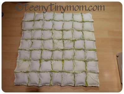 Selbstgemachtes Stoffgitter mit grünen Schnüren, ideal für kreative Dekorationen oder DIY-Projekte, auf Holzoberfläche gelegt.