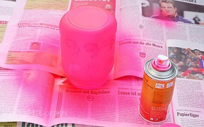 Buntes Windlicht in Hasenform, umgeben von Zeitungspapier, geeignet für Osterdekoration und kreative Bastelprojekte.