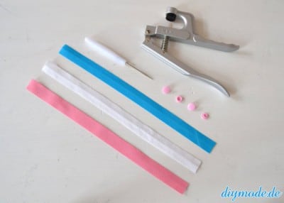 Bastelmaterialien für DIY Flechtarmband: Schrägband, Perlen, Zange, Bastelwerkzeug, kreative Handarbeit.