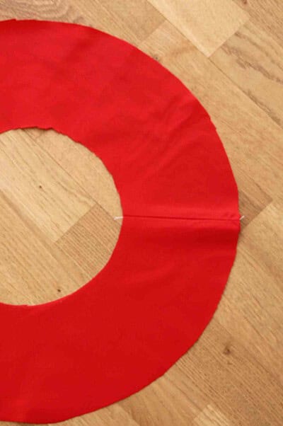 Roter Frühlingskranz aus Papier, ideal für Frühlingsdekorationen, handgemacht, mit einem kreisförmigen Design, auf Holzboden gelegt.