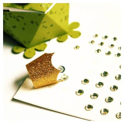 Goldene Geschenkverzierung mit Glitzer, Schmucksteinen und Geschenkbox für kreative Dekorationen bei Handmade Kultur.