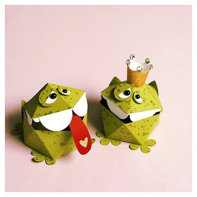 Zwei kreative Papierkrokodil-Figuren mit großen Augen, einem roten Zunge und einem kleinen goldenen Krönchen, ideal für kreative Bastelprojekte und Kinderdekorationen.