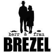 Silhouette eines Mannes und einer Frau mit Brezel- und Lippen-Icons, stilisiertes Logo für Handmadekultur, Fokus auf handgemachte Brezeln und kreative Handwerkskunst.