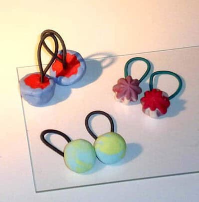 Zwei handgefertigte Manschettenknöpfe aus Kaltporzellan mit bunten Blumen- und Ballmotiven, ideal für elegante Anlässe und stilvolle Outfits.