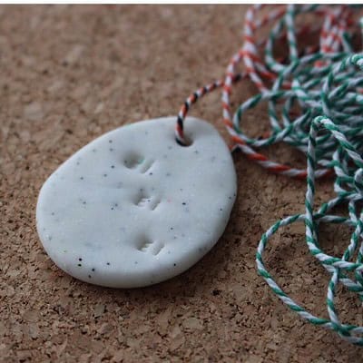 Handgemachter Osteranhänger aus Fimo in ovaler Form mit Loch und bunten Schnüren zum Aufhängen, geeignet für Osterdekorationen.