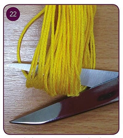 Gelbe Wollfäden, die um eine Schere gewickelt sind, für kreative Handwerksprojekte.