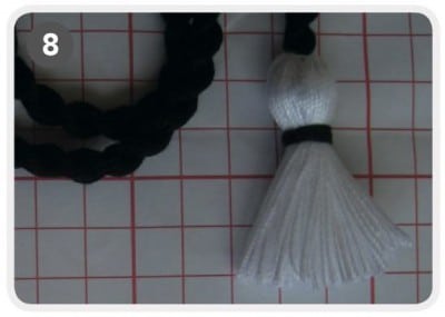 Handgefertigter Schmuckanhänger mit schwarzem Kordel und weißer Quaste, ideal für personalisierte Accessoires, kreative DIY-Projekte und handgemachten Schmuck.
