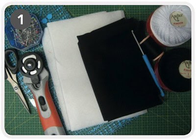 Nähzubehör, Stoffe und Werkzeuge für handgemachte Projekte, inklusive Nähmaschine, Fäden, Schere und Stecknadeln, auf einem grünen Schneidebrett.