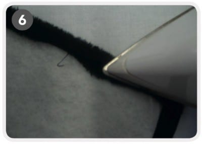 Nahaufnahme einer handgemachten Tablet-Hülle mit Stickerei, die auf einem grauen Stoff liegt, zeigt detailreiche Näharbeit und kreative Gestaltung.