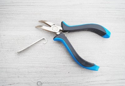 Kleine Zange und Haken für das Basteln von Besteck-Schlüsselanhängern, handgefertigt, mit Fokus auf Kreativität und Handwerkskunst.