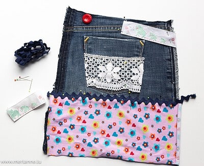 Recycling-Jeans mit buntem Stoff, Spitze und Nähzubehör für DIY-Projekt, nachhaltige Mode für Kinder, Handarbeit, kreative Nähideen, umweltfreundliche Kleidung.